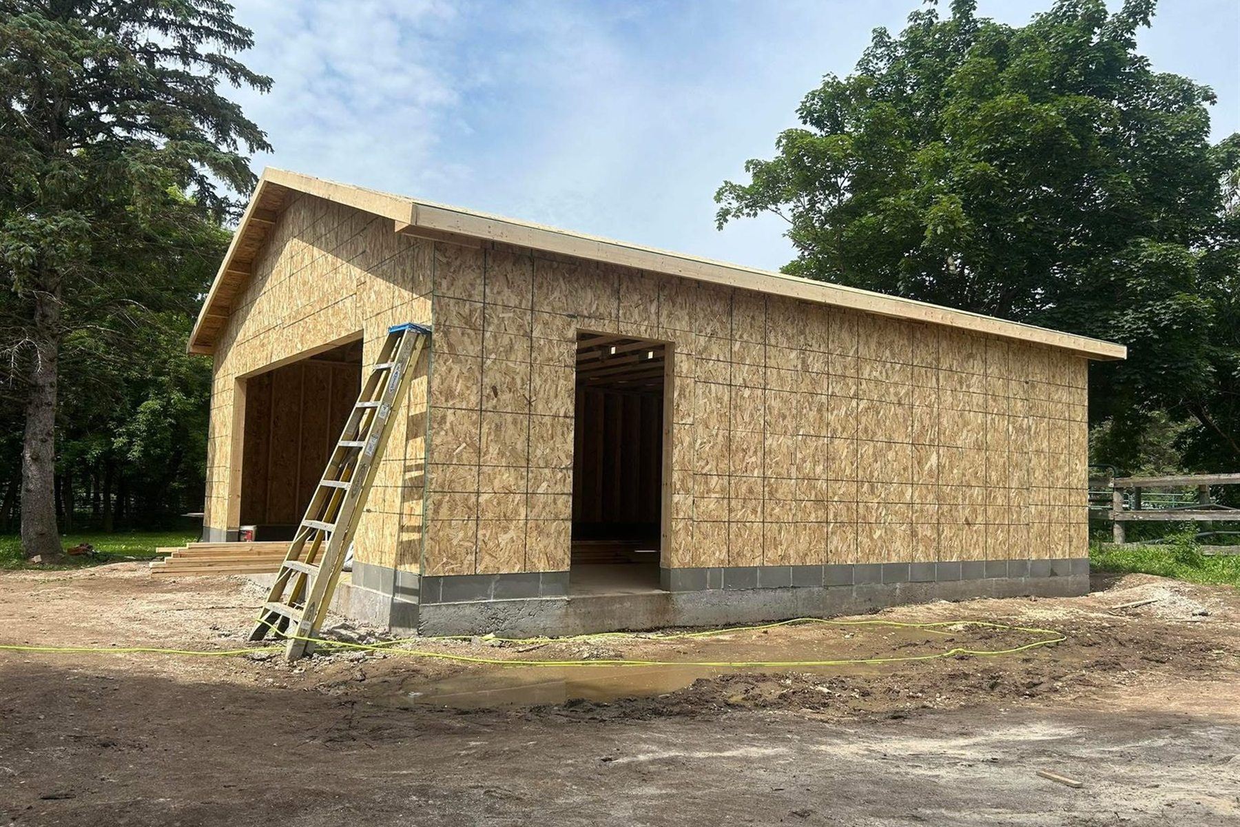 Detached garage sheathed and roofed, by New West Co